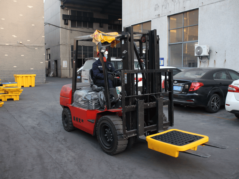 Forklift lifting a spill containment pallet for handling and loading operation